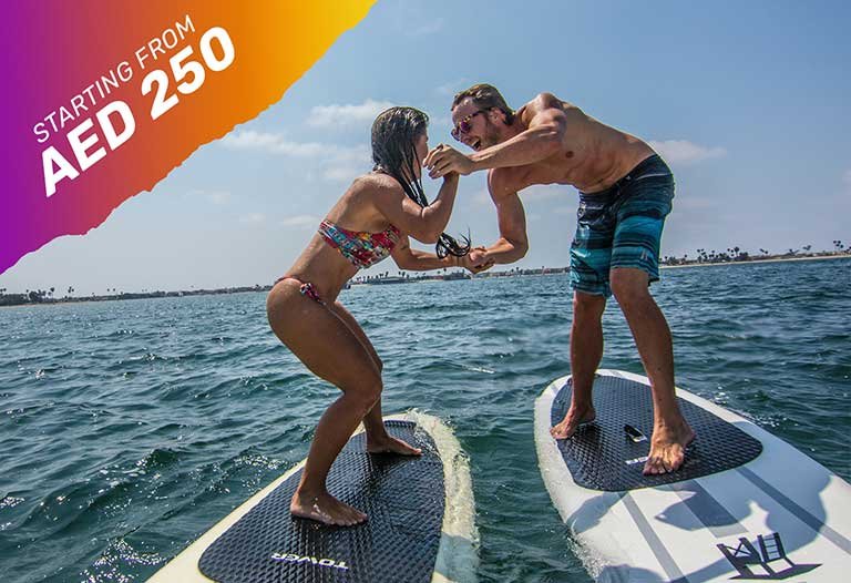 a man and a woman hold hands during paddleboarding Dubai experience
