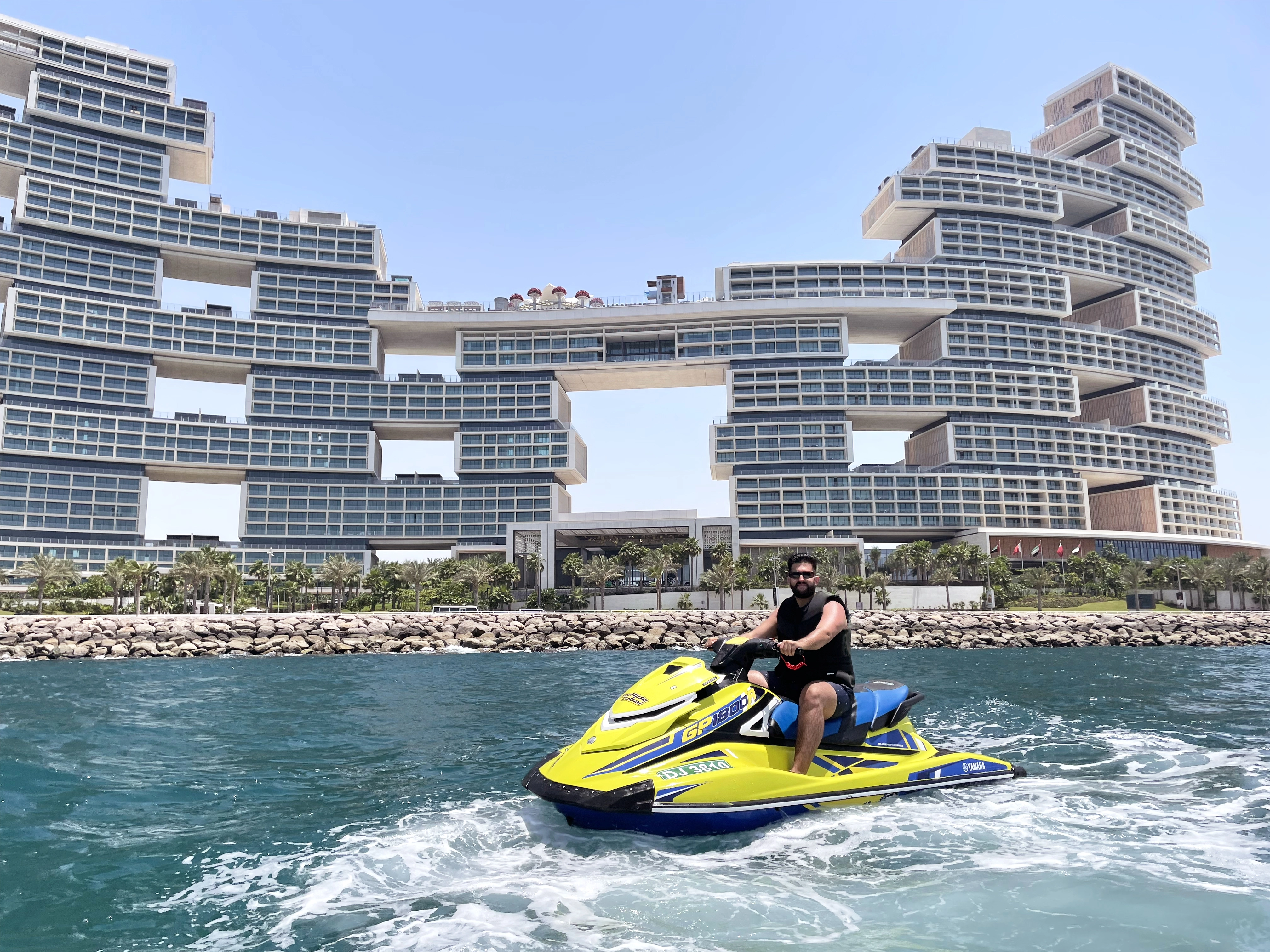 a man posing for a jetski dubai experience in front of The Royal Atlantis Hotel in Dubai