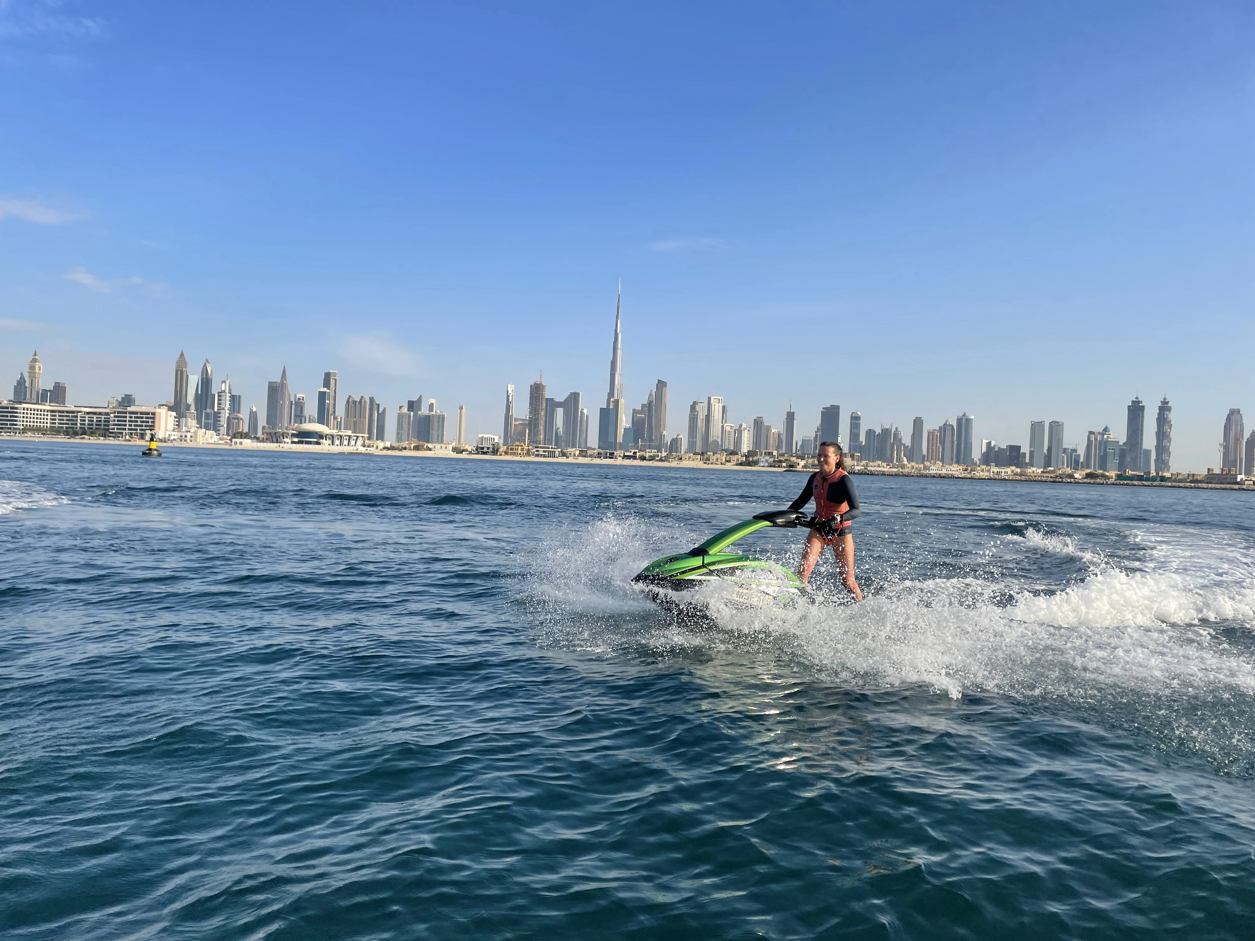 a lady enjoying stand up jetski in Dubai with burj khalifa on the background